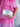 Silver clutch held by a hand wearing a pink dress with white floral embroidery.