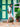 Woman holding a green handbag in front of a colorful building with green and pink doors.