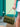 Green handbag with braided detail and gold chain handle held by a person against a teal door.
