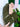 Green clutch with a chain strap held by a hand against a blurred background