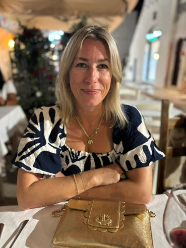Woman sitting at a table with a gold Finn Scallop handbag by Elyse & i in a casual setting