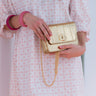 Person holding an Elyse & i  gold Otis handbag with a white background