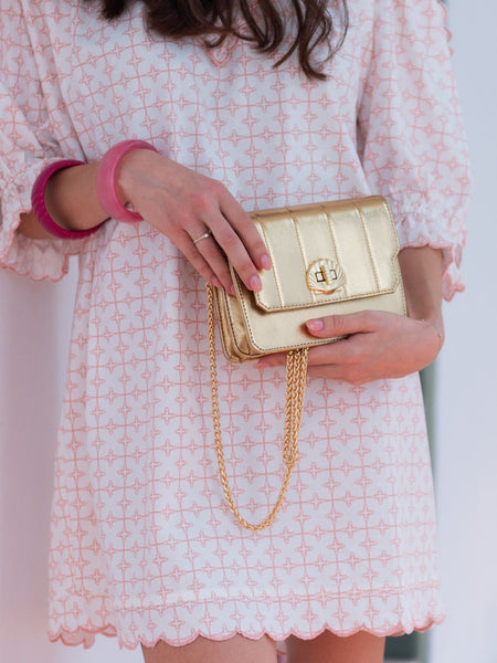 Person holding an Elyse & i  gold Otis handbag with a white background