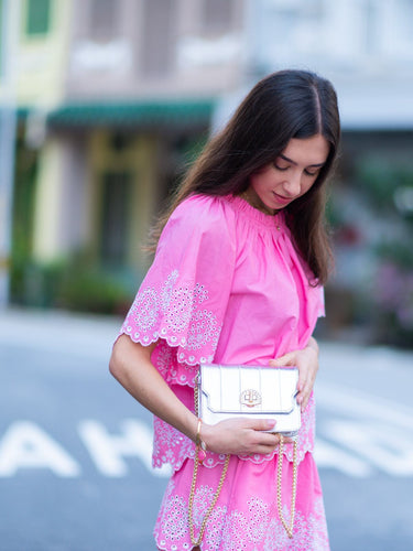 Woman in a pink dress holding the silver Otis bag with shell turn lock by Elyse & i  on a street.