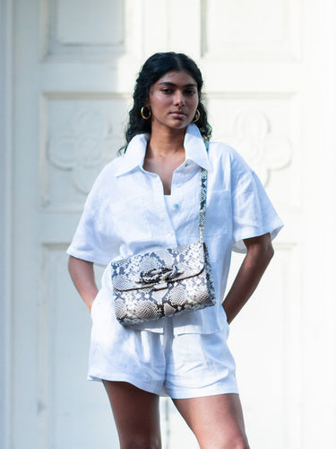 Model in white top and shorts wearing a bag by Elyse & i as a crossbody, called Theo Knot. 