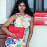 Woman holding an Elyse & i red clutch in front of a building with a red mailbox.
