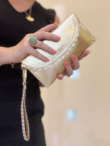 Gold purse with scallop detail and wrist strap. 