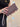 Mauve purse with scallop details being held by a lady with green ring on. 