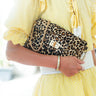 Person wearing a yellow checkered outfit holding a leopard print handbag.
