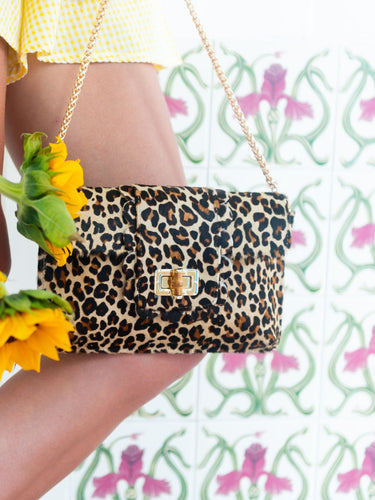 Leopard print handbag held by a person with a floral background