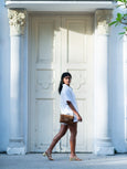 Woman walking in front of a large ornate door with classical architecture wearing a cheetah print Finn Scallop clutch by Elyse & i.