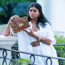 Woman holding a cheetah print Finn Scallop clutch by Elyse & i in an outdoor setting