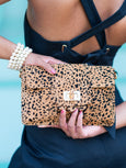 Cheetah print Finn Scallop clutch by Elyse & i handbag held by a person against a light blue background