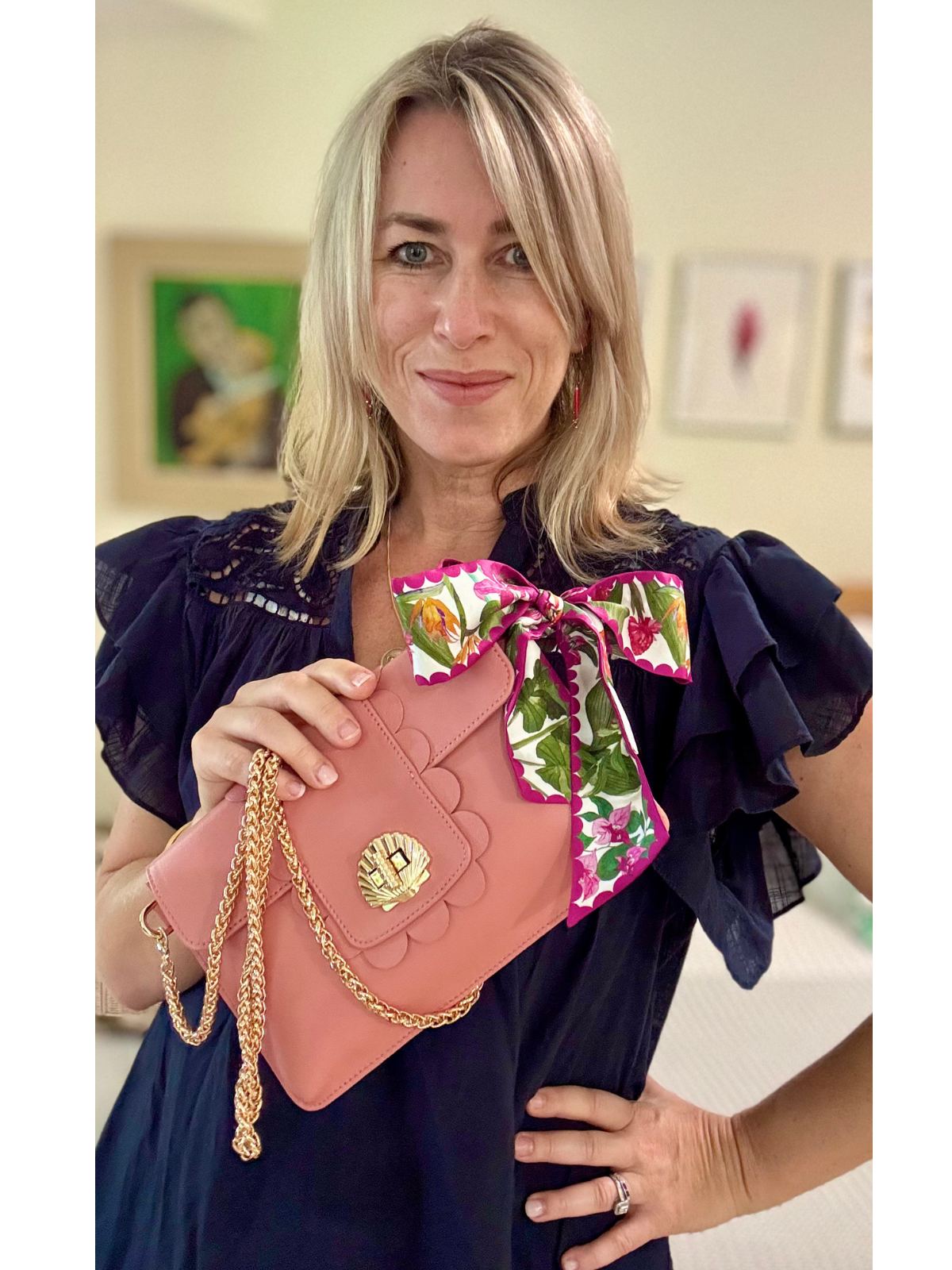 Woman holding a pink Elyse & i 
handbag with a floral ribbon, indoors.