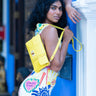 Woman holding a yellow Finn Elyse & i bag against a blue door