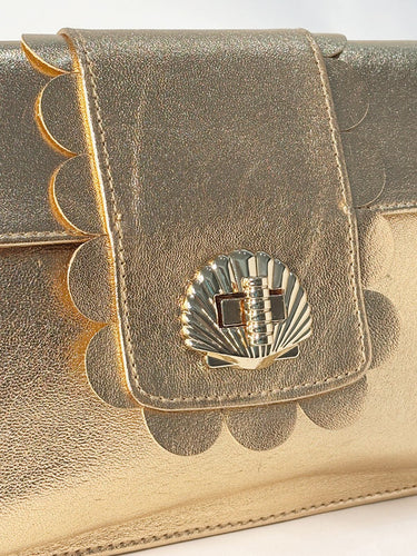 Gold metallic clutch bag with decorative emblem on a white background