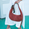 Person holding a brown  Elyse & i Martha hobo suede handbag with a white background