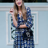 Model wearing Elyse & i Nell Knot bag in black nappa leather with gold knot detail, styled crossbody with blue patterned dress.