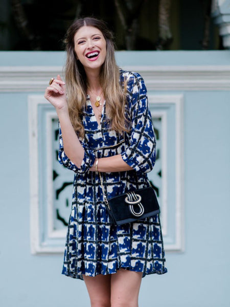 Model wearing Elyse & i Nell Knot bag in black nappa leather with gold knot detail, styled crossbody with blue patterned dress.