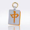 A rectangular leather keychain or luggage tag in the shape of a mahjong tile with the dragon symbol, attached to a gold metal key ring, shown on a reflective white background.
