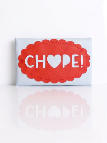 A light blue leather tissue holder with a red scalloped oval patch featuring the word 'CHOPE!' with a heart replacing the O, set against a white background with a soft reflection.