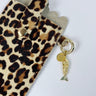 Leopard print phone case with a gold charm on a white background