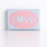 A light blue leather tissue holder with a pink scalloped oval patch on the front featuring the word 'LOVE' with a heart replacing the 'O'.
