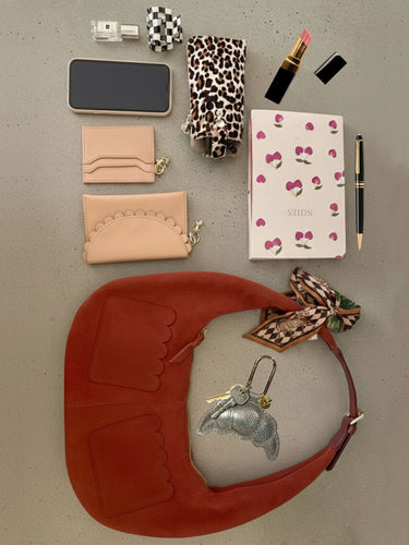 Collection of small accessories including a phone case, wallet, notebook, and keychain on a gray surface.
