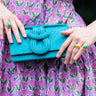 Person holding a blue clutch with a purple floral dress