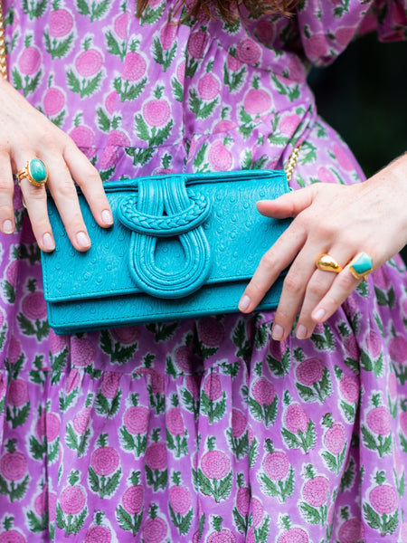 Person holding a blue clutch with a purple floral dress