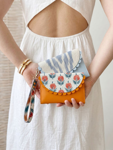 Person holding a colorful handbag with floral design and striped pattern.