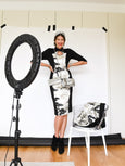 Woman posing with a ring light and fashion items in a studio setting