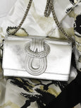Silver handbag with braided detail on a patterned fabric background