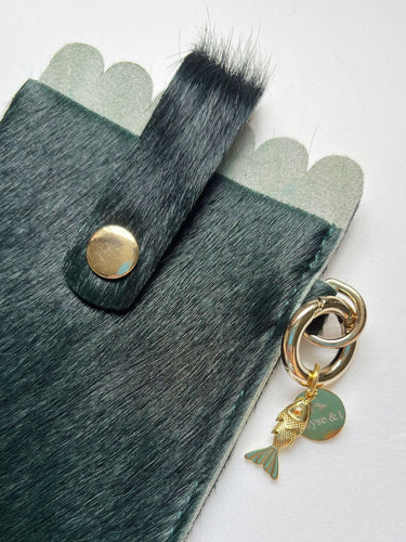 Close up of forest green glasses case with gold lucky fish charm