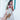 Woman in a white dress with a bambi print bag and gold clutch walking outdoors.