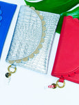Two wallets, one silver with a textured pattern and gold charm, the other red with a matching gold charm, on a white background.